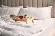 © New Africa - Wooden tray with breakfast and book near soft blanket on bed