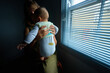 Young mother by window holding baby with soiled diaper