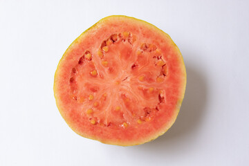 Red guava cut in half, showing the seeds and isolated on white background