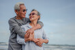 Senior couple embrace on the beach at not sunny day, plan life insurance with the concept of happy retirement.