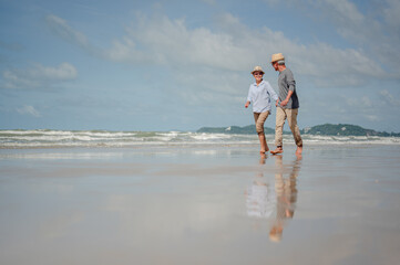 Wall Mural - Senior couple running on the beach at sunny day. Plan life insurance with the concept of happy retirement.