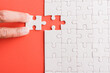 © sorapop - Top view flat lay of hand-holding last piece white paper jigsaw puzzle game last pieces put to place for solve problem complete mission, studio shot on a pink background, quiz calculation concept