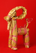 Side view of traditional Christmas billy goat straw decorartion on red background.
