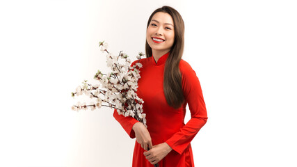 Portrait of Asian girl hands holding  peach blossom, in traditional red ao dai standing on plain background.