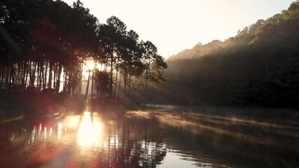 amazing morning sunlight at pang ung lake with rowing boat and fog floating above the water surface,