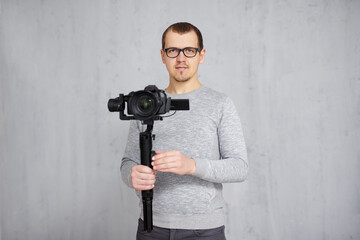 Wall Mural - professional videographer holding dslr camera on 3-axis gimbal over grey concrete wall