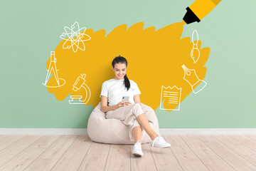 Young woman with mobile phone sitting near color wall. Concept of online education