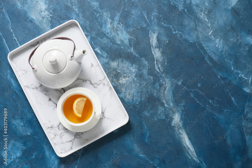 Tray with teapot and cup on color background