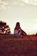 © astrosystem - Silhouette of a woman sitting on a field.