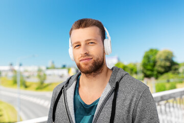 Poster - fitness, sport and lifestyle concept - young man in headphones listening to music outdoors