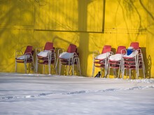 Stacked Vintage Chairs Covered With Snow Are Leaning On A Yellow Wooden Wall
