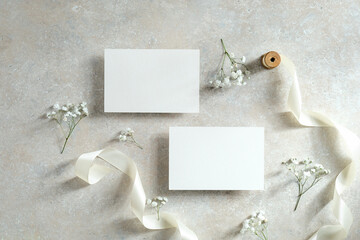 Wedding invitation cards template. Flat lay, top view blank paper cards, ribbon, flower on stone table.