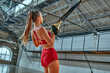 © Valerii Apetroaiei - Beautiful caucasian woman in sportswear trains with trx fitness belts in the gym. Beautiful lady exercising muscle sling or hanging straps.