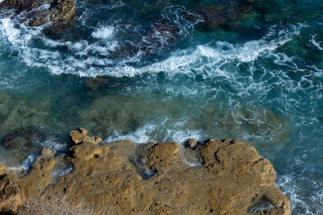 Wall Mural - Top down view of splashing waves at the rocks in the ocean or sea.