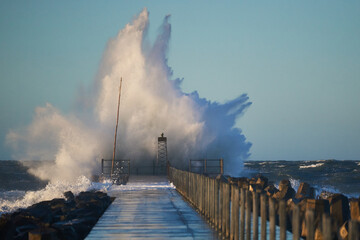 dramatic, strong waves and foam spray hit the pier in vorupoer during storm on the north sea coast o