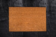Natural coir doormat on antique wooden texture, background