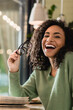 © LIGHTFIELD STUDIOS - african american woman holding eyeglasses and laughing in cafe