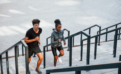 Wall Mural - European man and african american woman in sportive clothes have workout together