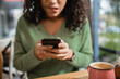 © LIGHTFIELD STUDIOS - cup of latte near worried african american woman biting lips while texting on smartphone on blurred foreground