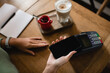 © LIGHTFIELD STUDIOS - cropped view of african american woman paying with smartphone in cafe