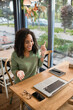 © LIGHTFIELD STUDIOS - happy african american woman pointing with finger while looking at laptop