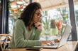 © LIGHTFIELD STUDIOS - Concentrated African American woman in glasses using laptop in cafe