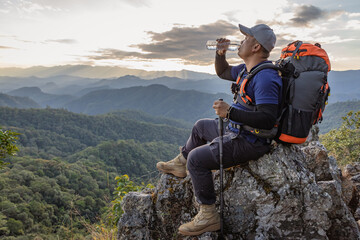 Wall Mural - Hiker relaxing on mountain  top and drinking bottled water