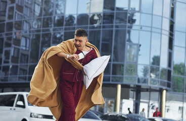 Running, late for the work. Young man in pajama is outdoors on the street. Feels sleepy