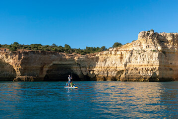 Wall Mural - father and twho young children paddle on a SUP board along the Algarve coast in Portugal