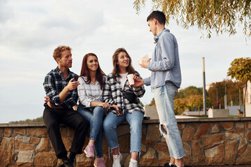 Wall Mural - Coffee time. Group of young cheerful friends that is outdoors having fun together