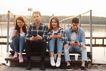 Wall Mural - Near the lake. Group of young cheerful friends that is outdoors having fun together