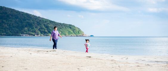 Wall Mural - Children walk with a ball on the beach. A father followed behind his daughter. The family rested at the sea during a long vacation. In the summer.