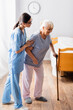 © LIGHTFIELD STUDIOS - asian nurse helping aged woman walking with stick in hospital