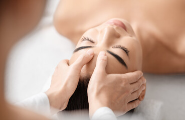 Wall Mural - Young attractive korean woman getting acupressure massage treatment in spa salon