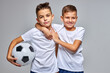 © Roman - kid boys go in for soccer sport professionally, stand hugging each other, have fun, smile at camera, holding ball in hands, isolated portrait