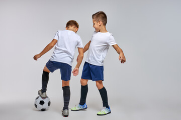 Wall Mural - children soccer team on training, two boys practicing game with a soccer ball in studio. training football session for children on soccer camp. young boy improving dribbling skills