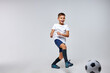 © Roman - boy soccer player playing with ball, kicking it, training before match. isolated in studio, wearing uniform
