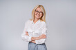 © InsideCreativeHouse - Smiling confident aged business woman in formal clothing with arms crossed isolated over grey background