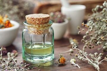 Wall Mural - Essential oil bottle, mortars of dry medicinal herbs and old book on background.