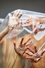 close-up photo of hands of people wants to get out of the confinement of plastic waste, in plastic b