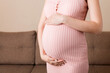 © sosiukin - Pregnancy woman in beautiful dress standing on the home