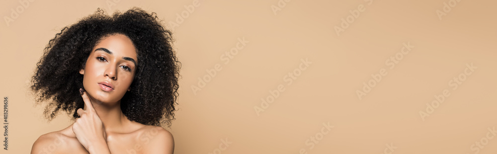 young african american woman with bare shoulders looking at camera isolated on beige, banner - obrazy, fototapety, plakaty 