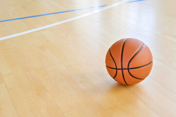 Canvas Print - A basketball on the wooden floor as background. Team sport concept