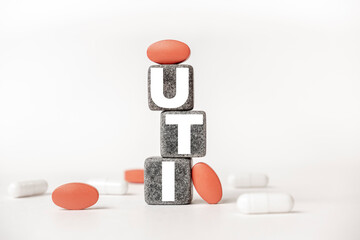 Wall Mural - a group of white and red pills and cubes with the word UTI Urinary tract infection on them, white background. Concept carehealth, treatment, therapy.