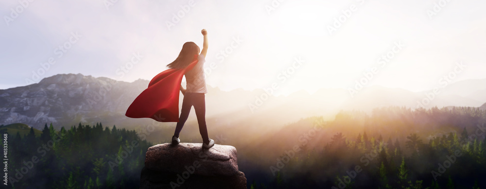 little girl dreaming of being a superhero in a beautiful mountain landscape with a raised fist - obrazy, fototapety, plakaty 