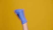 Close Up Of Angry Unrecognizable Man Shaking Fist In Medical Protection Gloves Aside, Isolated On Yellow Studio Background With Copy Space. Threat Gesture, Concept Of Aggression, Warning, Punishment