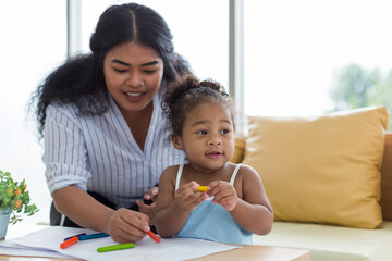 happy african american mother and her little daughter. mother teaching her daughter drawing and pain