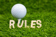 Rules word with golf ball behind for rules of golf on green grass