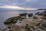 Fototapeta Morze - Cloudy sunrise on rocky sea coast, long exposure