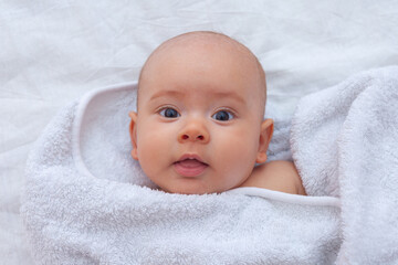 Beautiful smiling baby girl baby wrapped in white towel